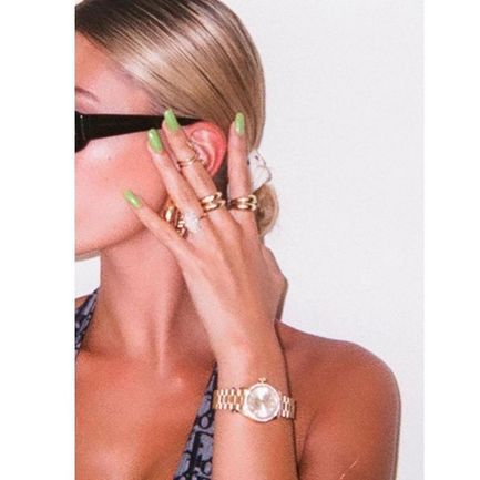 Partial view of a woman with green nails, jewelry, and a watch, minus her face. If a young man is in the shot, he's identified as Justin Bieber.