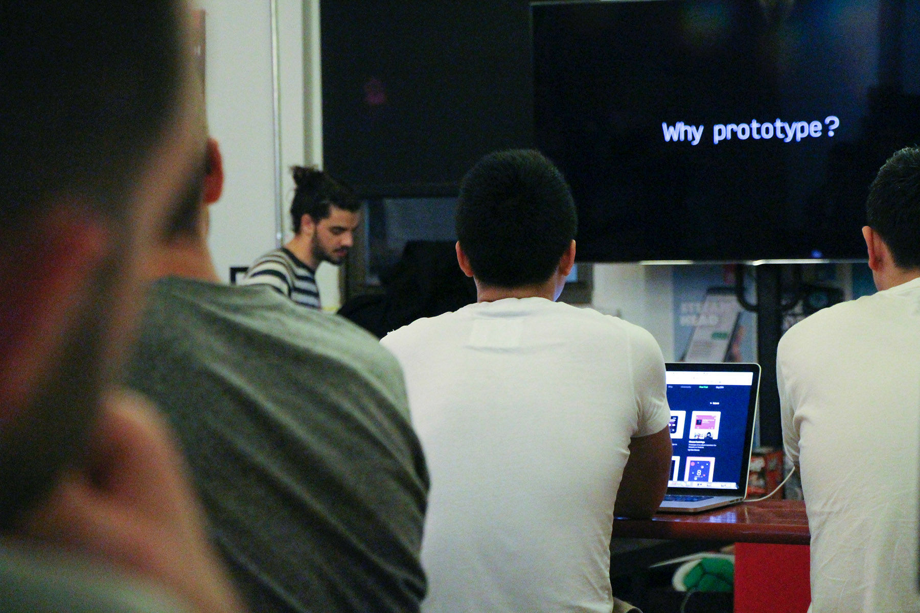 A group of people at a meet up, watching a presentation