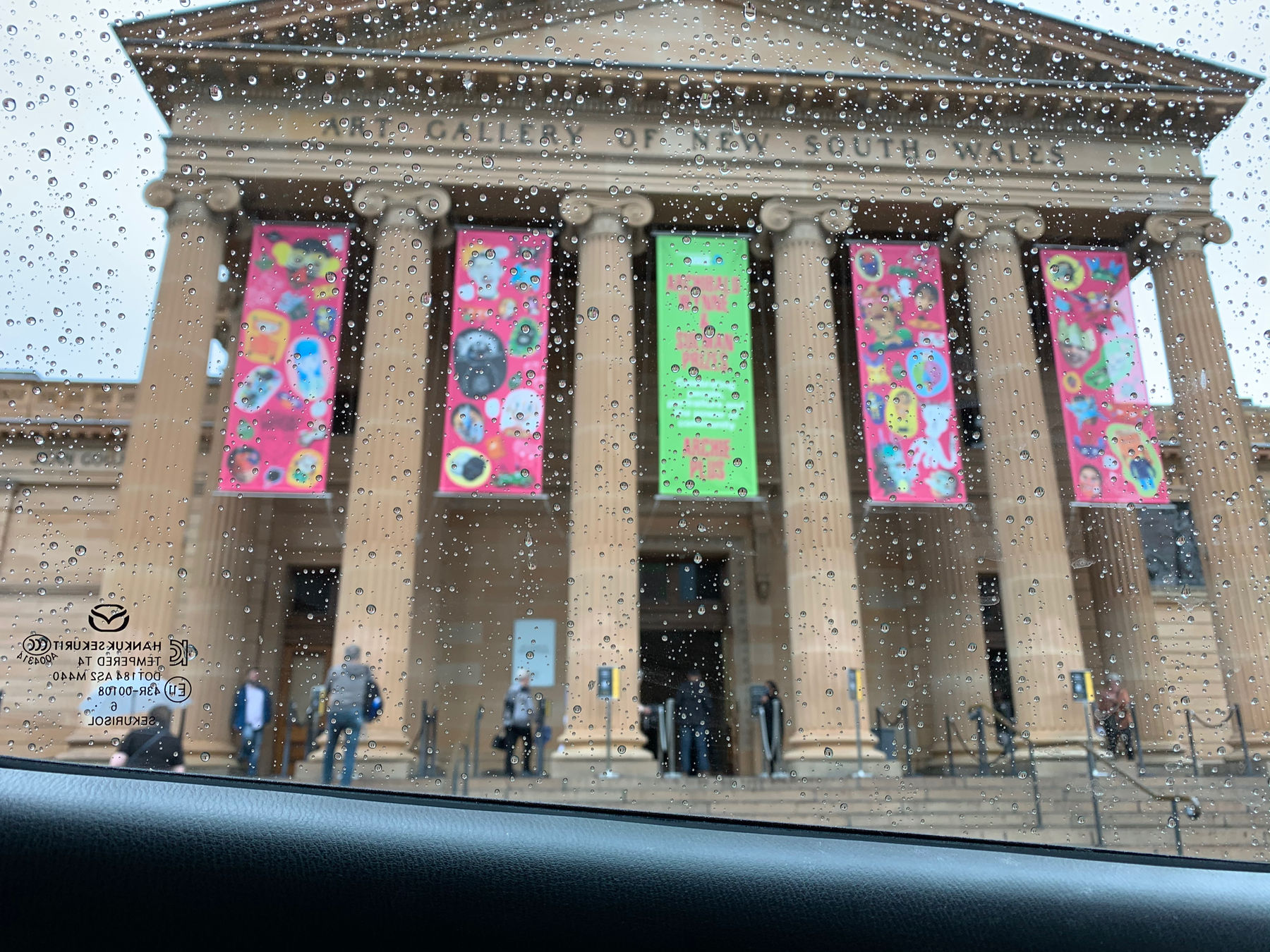 The front entrance of the art gallery viewed from a rainy car window