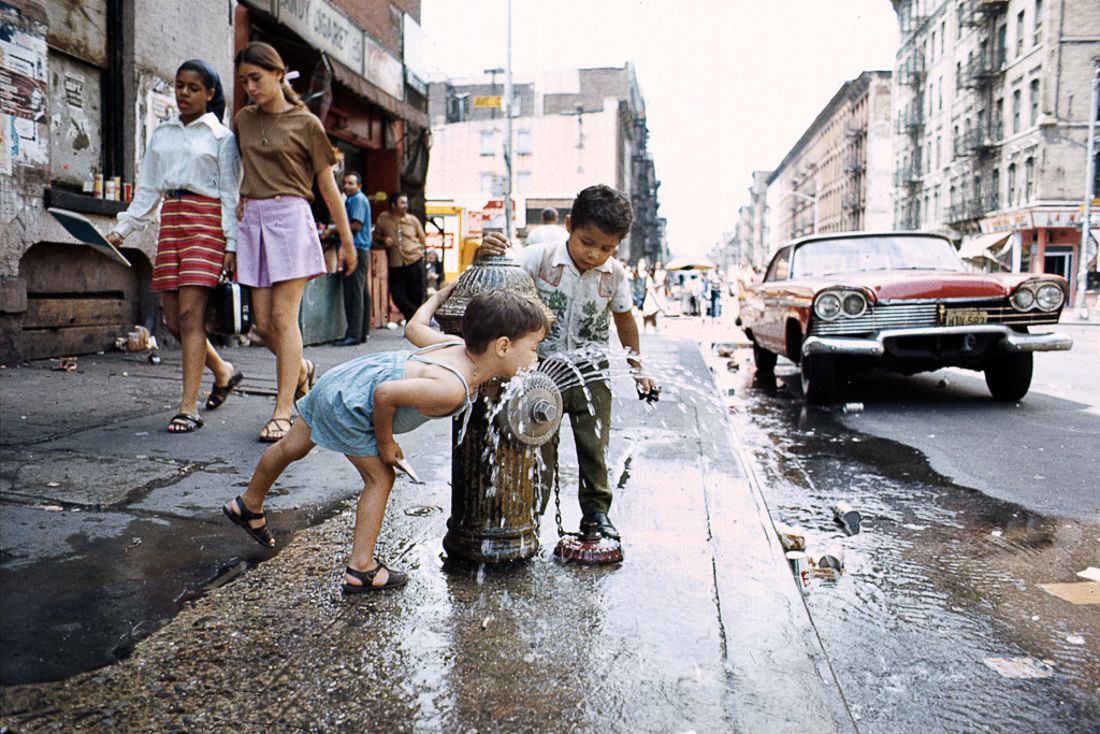 Two kids playing with a fire hydrant