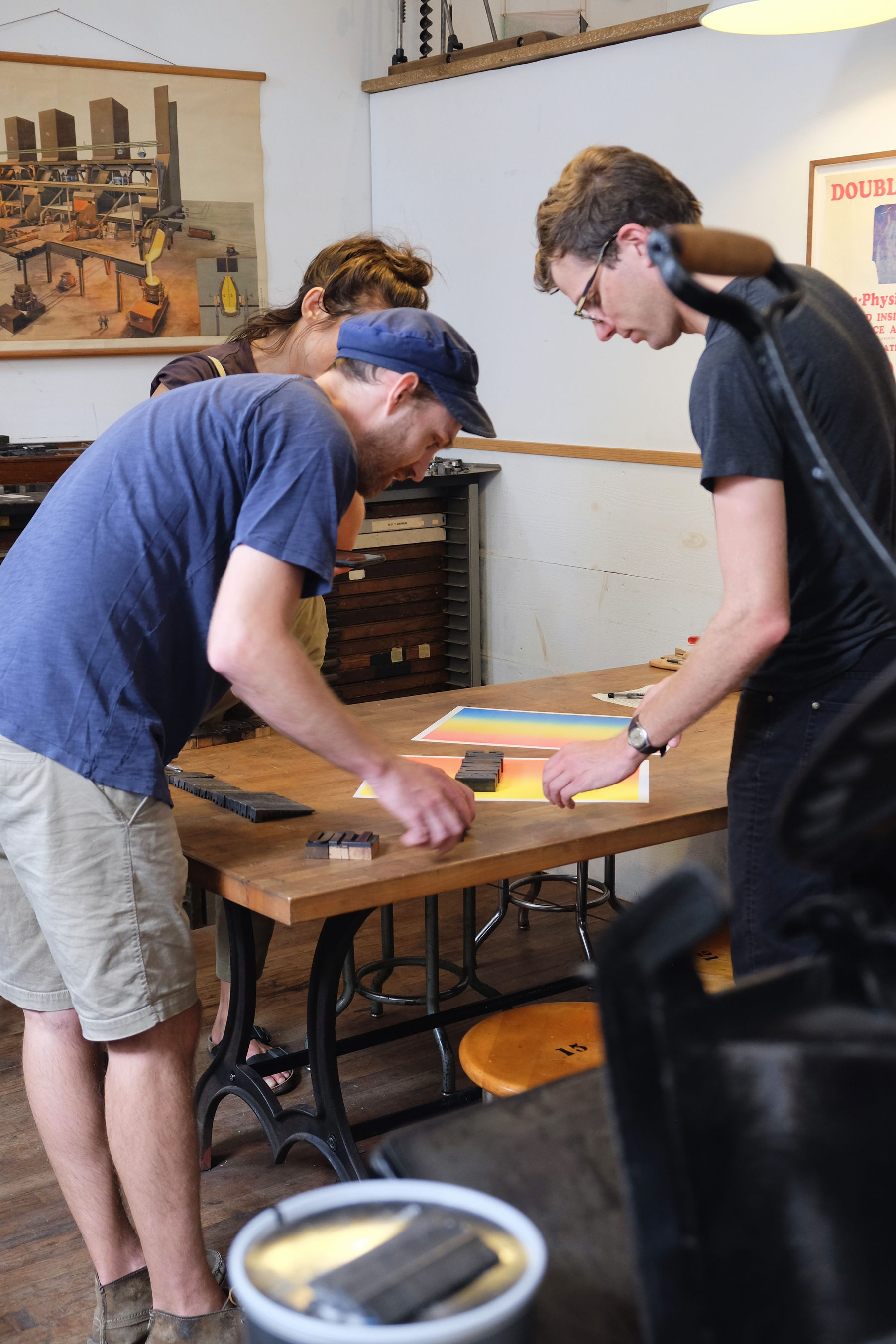 Three people aligning type on a piece of paper