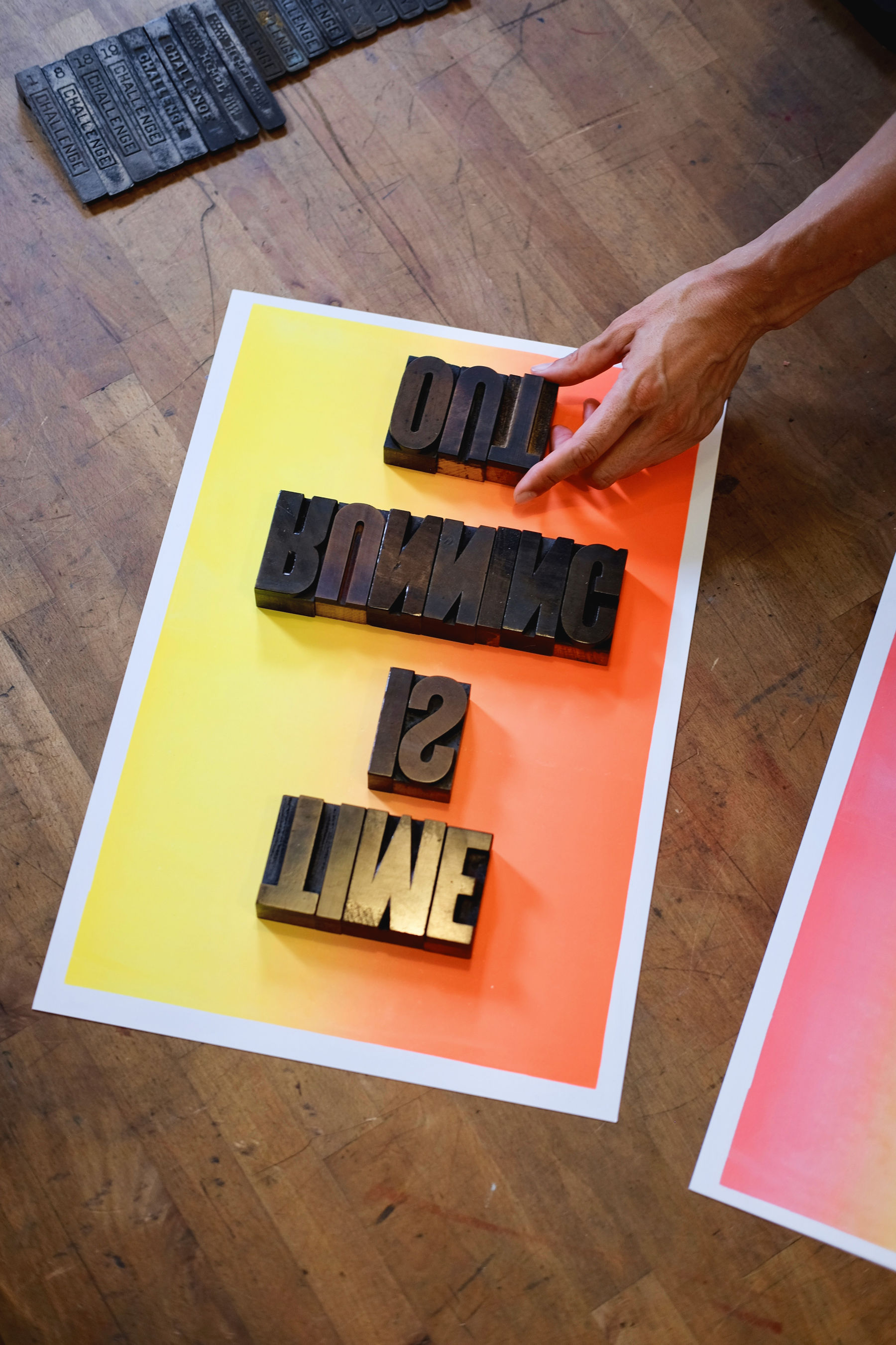 A person's hand arranging type on a piece of paper
