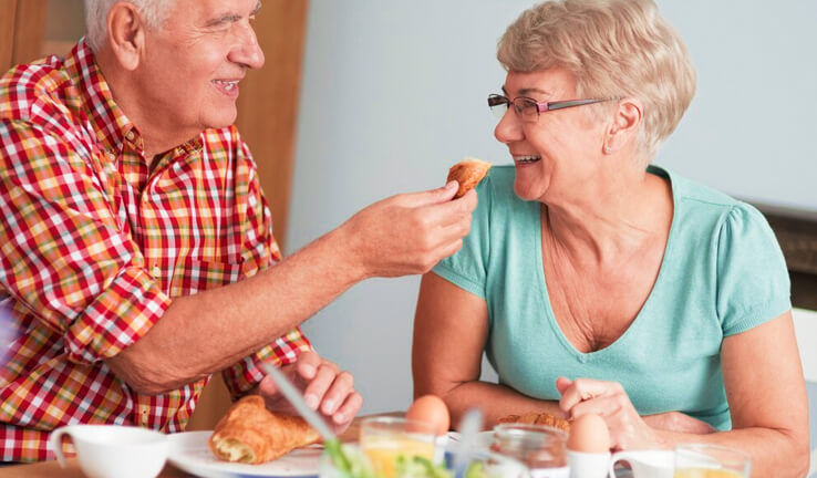 Casal de idosos comendo.