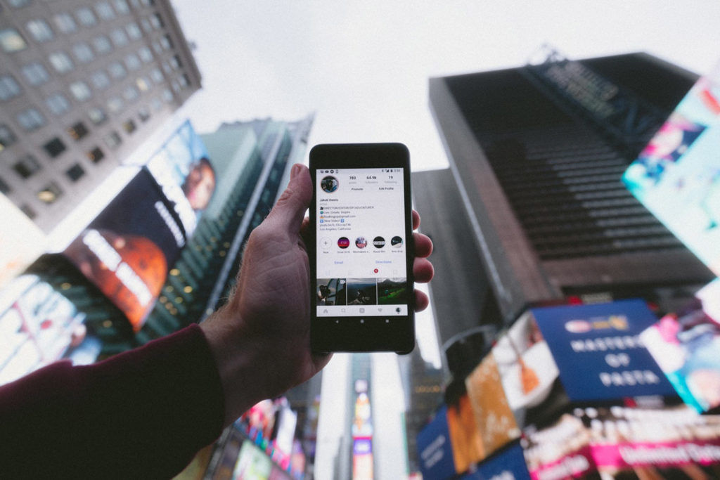 Mobile Social Media posts Man holding iphone on instagram in a city
