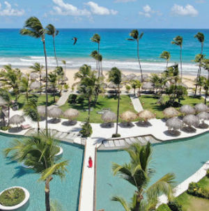 Piscina, palmeras y playa en un resort de lujo en Punta Cana