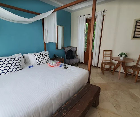 Vista desde un balcón con muebles de mimbre hacia un jardín tropical y el mar Caribe