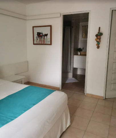 Vista aérea de un hotel boutique con piscina, jardín con flores, y edificio de varios niveles con escaleras exteriores y balcones
