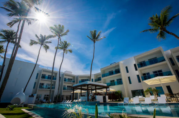 "Vista soleada de la piscina y bar de un resort moderno en República Dominicana, accesible cómodamente con Taxi Dominicana."