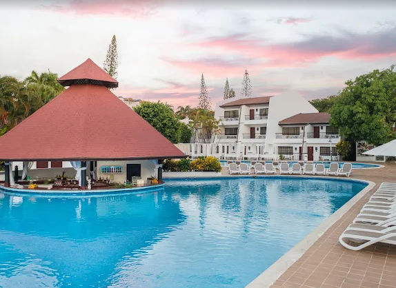 An outdoor pool at a tropical resort during sunset.