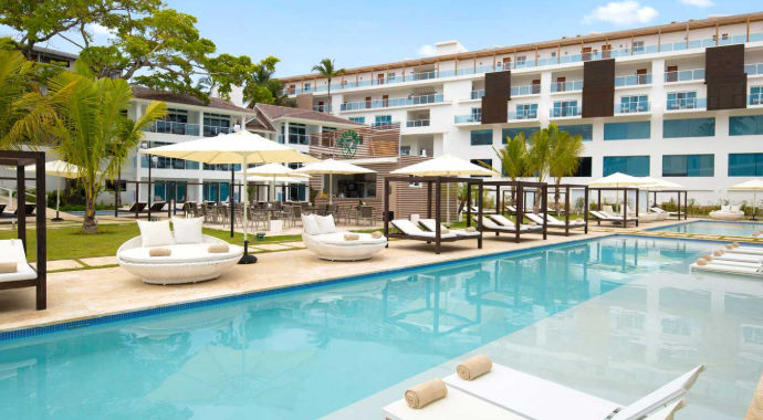 Vista soleada de la piscina y bar de un resort moderno en República Dominicana, accesible cómodamente con Taxi Dominicana.