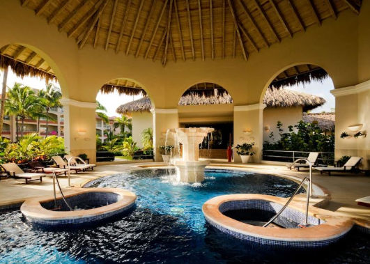 Vista panorámica de un exclusivo resort en Punta Cana, resaltando sus elegantes instalaciones, piscinas rodeadas de vegetación tropical y el ambiente relajante ideal para unas vacaciones de lujo.