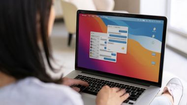 A woman operates a laptop with a vibrant screen showing steps for copying and pasting on a Mac computer.