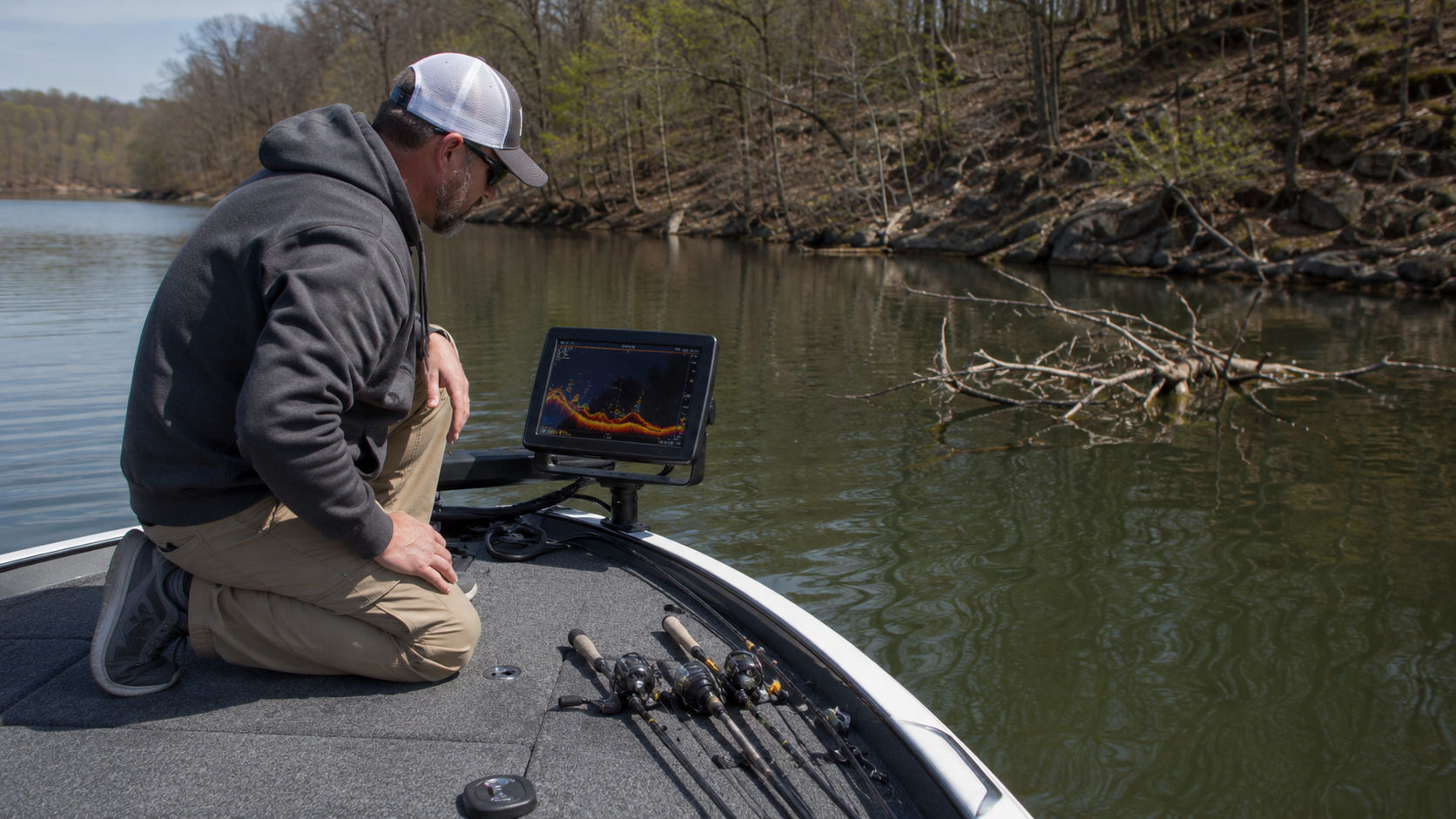 Crappie angler using a fish finder to locate fish and submerged structure