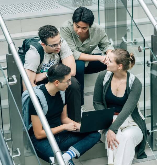 A Group Of Students Sat On A Stairs Chatting