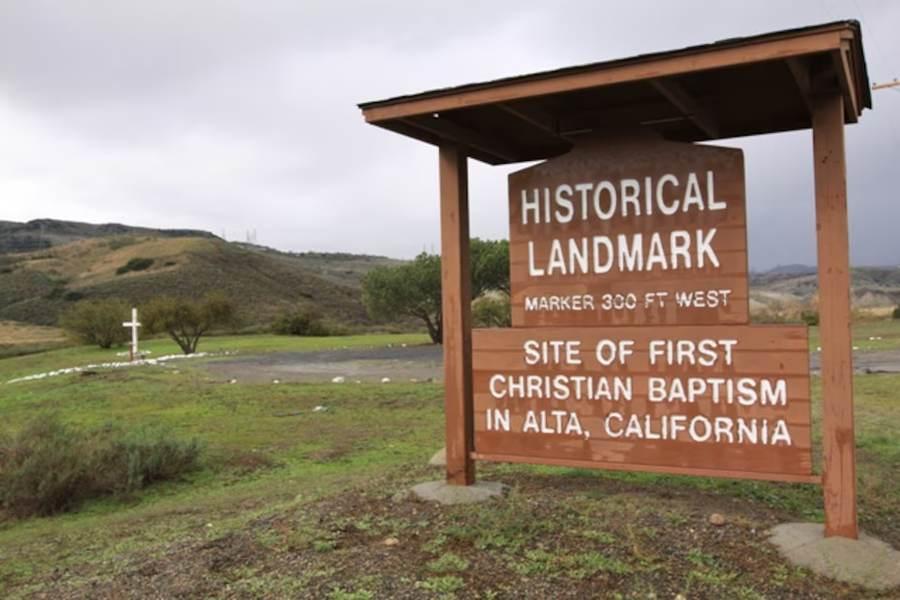 A historical landmark sign on the base marking the site of the first Christian baptism in Alta California.