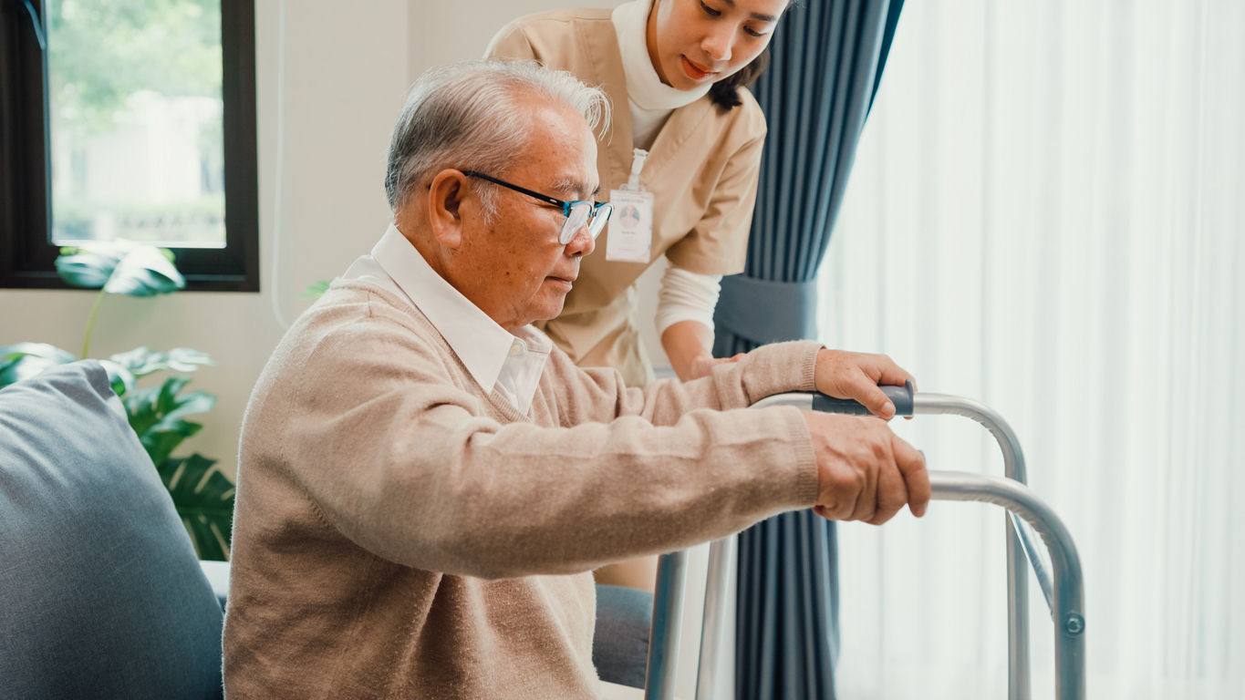 Home health aide helping older man with walker