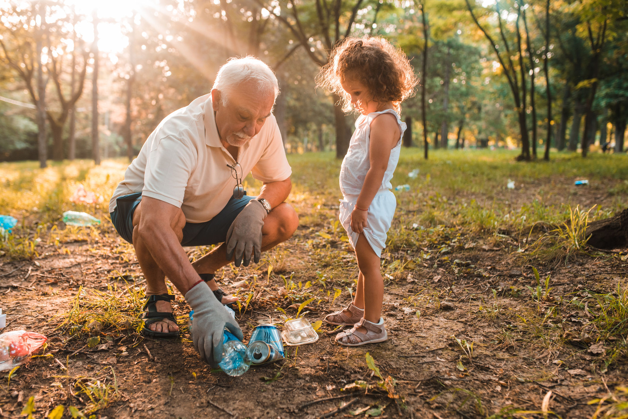 Older man volunteering to clean up trash with his granddaughter