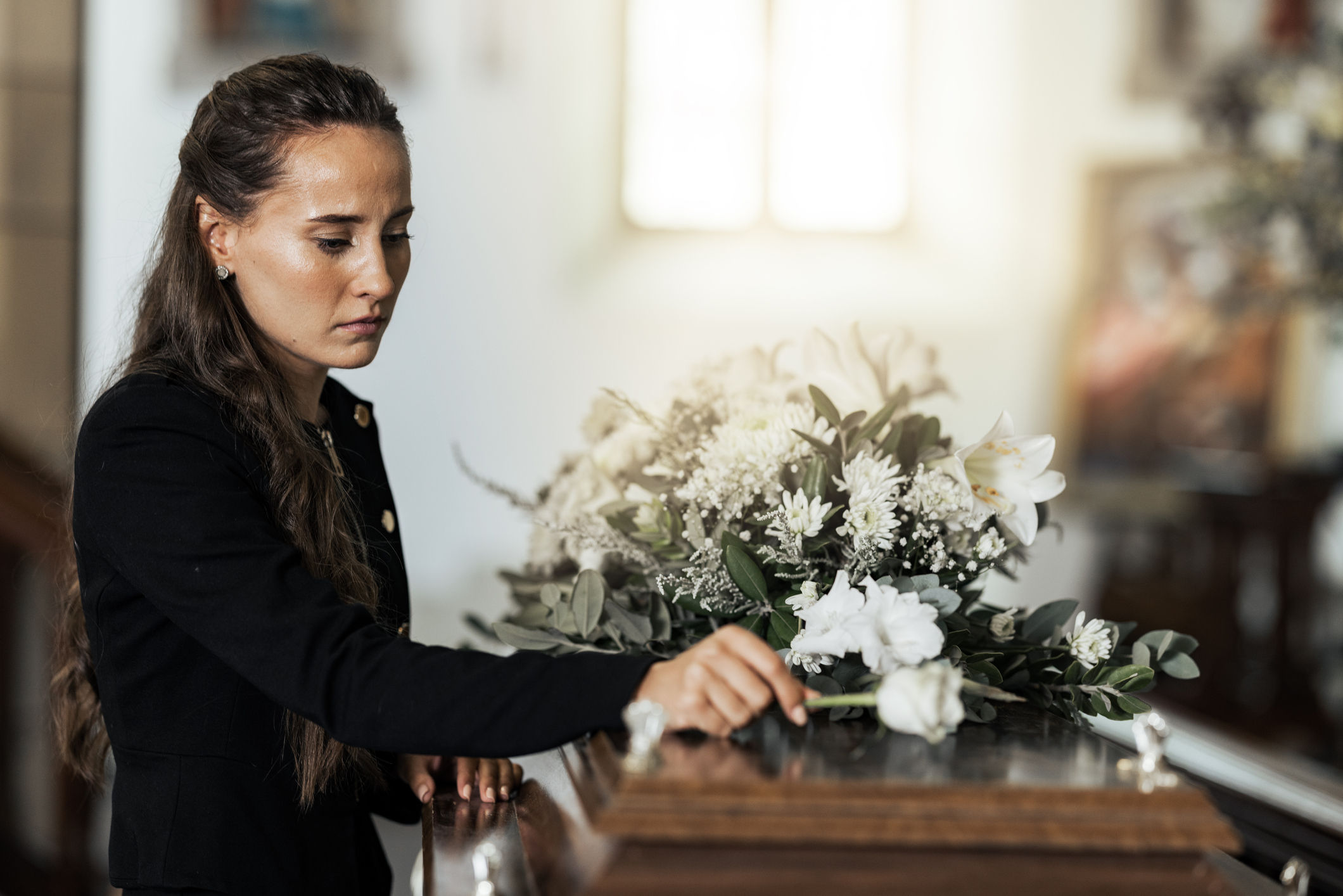 Woman at funeral placing flowers on a casket