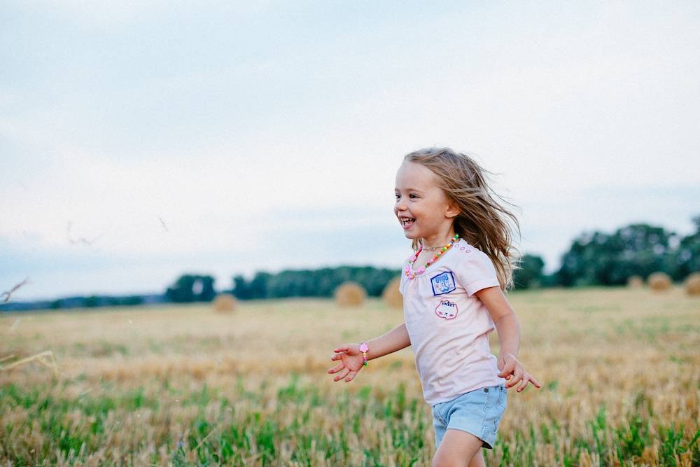 little girl running across a field wild and free