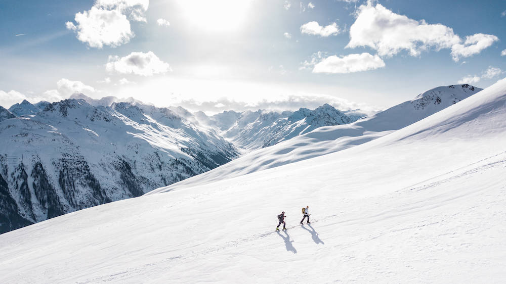 two people skiing together up a snowy mountain