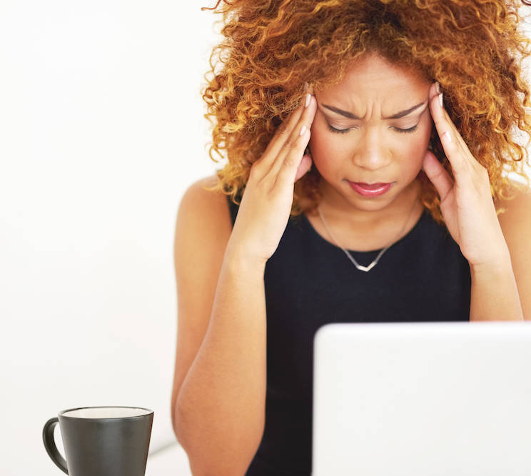 Shot of a young businesswoman suffering from a headache at work