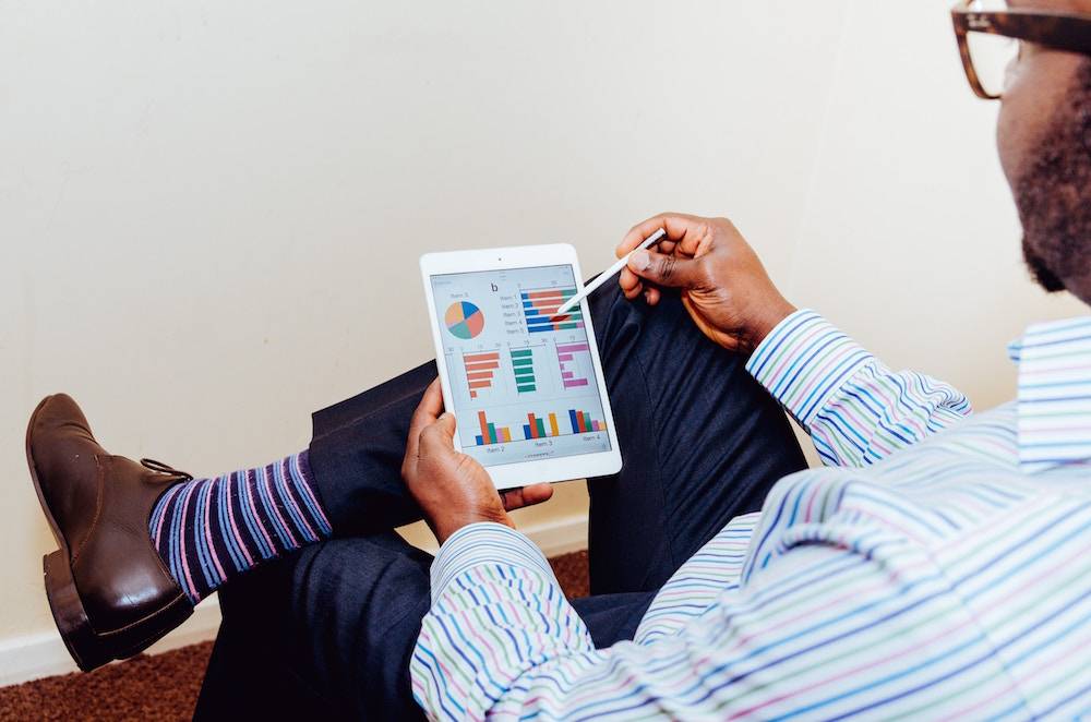 how to use google analytics - african american man sitting and studying his website analytics on a tablet device