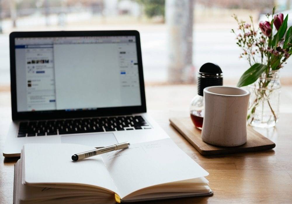 How to Get People to Read Your Blog: desk with laptop, flowers, and coffee