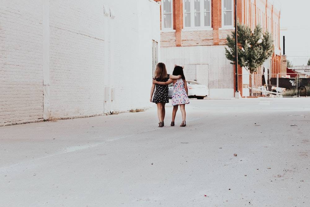 two little girls walking with their arms around each other