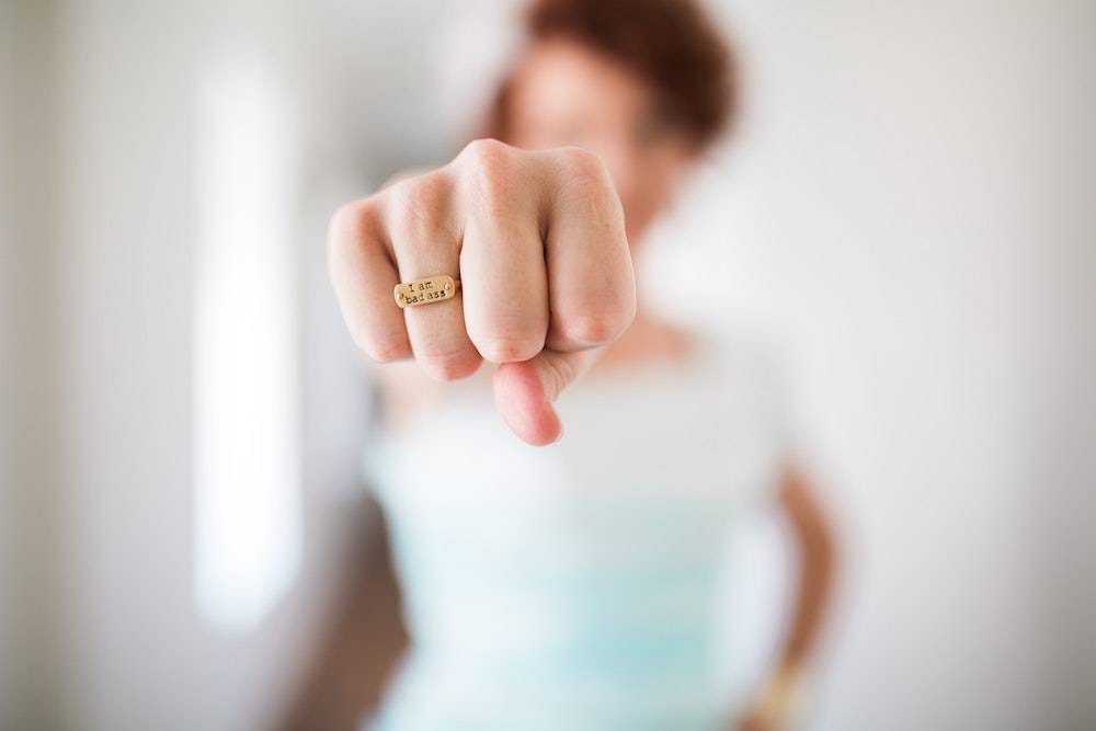 a woman with her fist out powerfully, ring says "I am a badass"