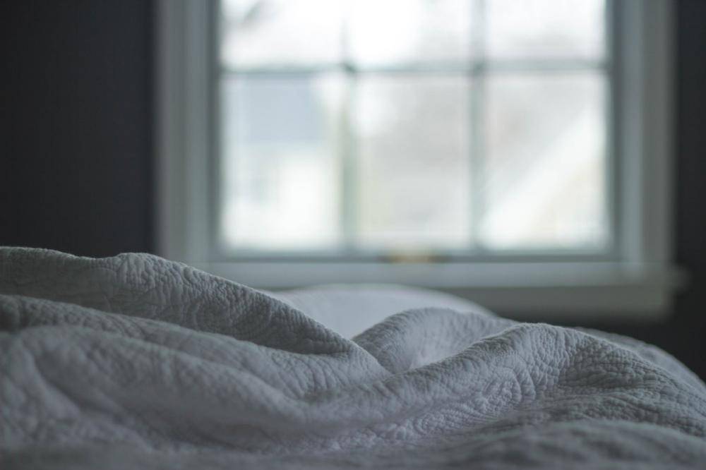 How to Start Your Day: a peaceful looking scene of blankets on a bed with a sunny window behind