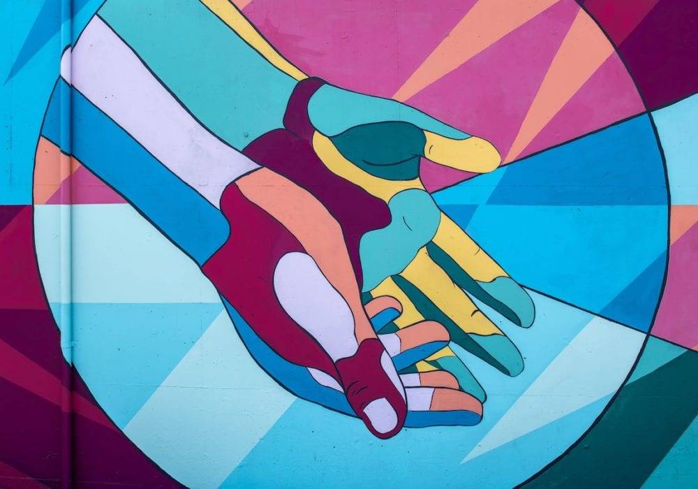 Feeling Disconnected From People: a mural of two hands open palm up with lots of colors