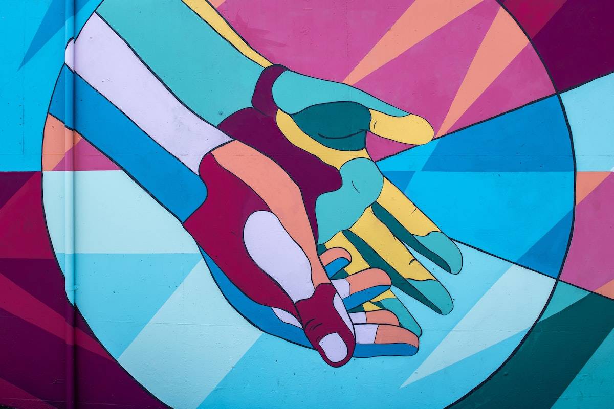 Feeling Disconnected From People: a mural of two connected hands open palm up with lots of colors