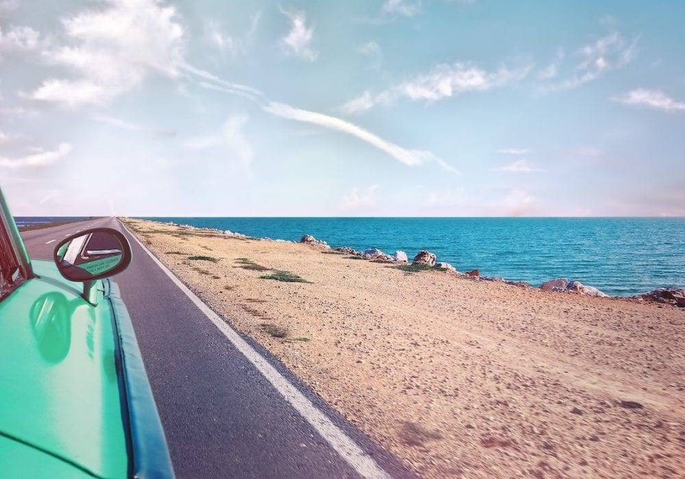 how to have the best vacation ever: teal car driving by the sand and the ocean