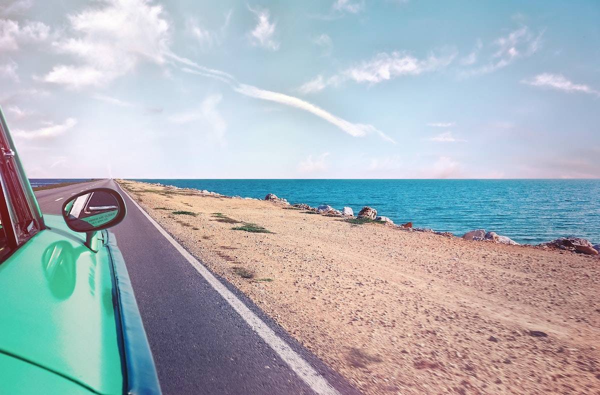 how to have the best vacation ever: teal car driving by the sand and the ocean