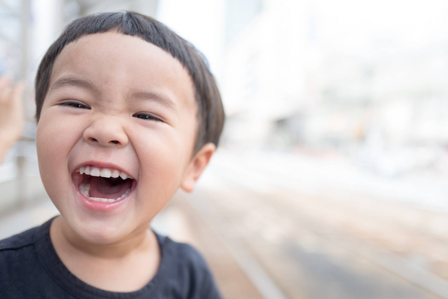 how to laugh more: a young Asian boy laughing and smiling