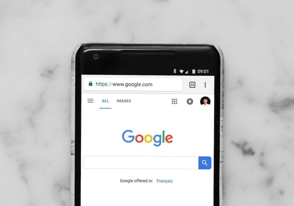 Best WordPress plugins for SEO and Better Page rank: Google PoGoogle front page on a cell phone sitting on top of a marble countertop