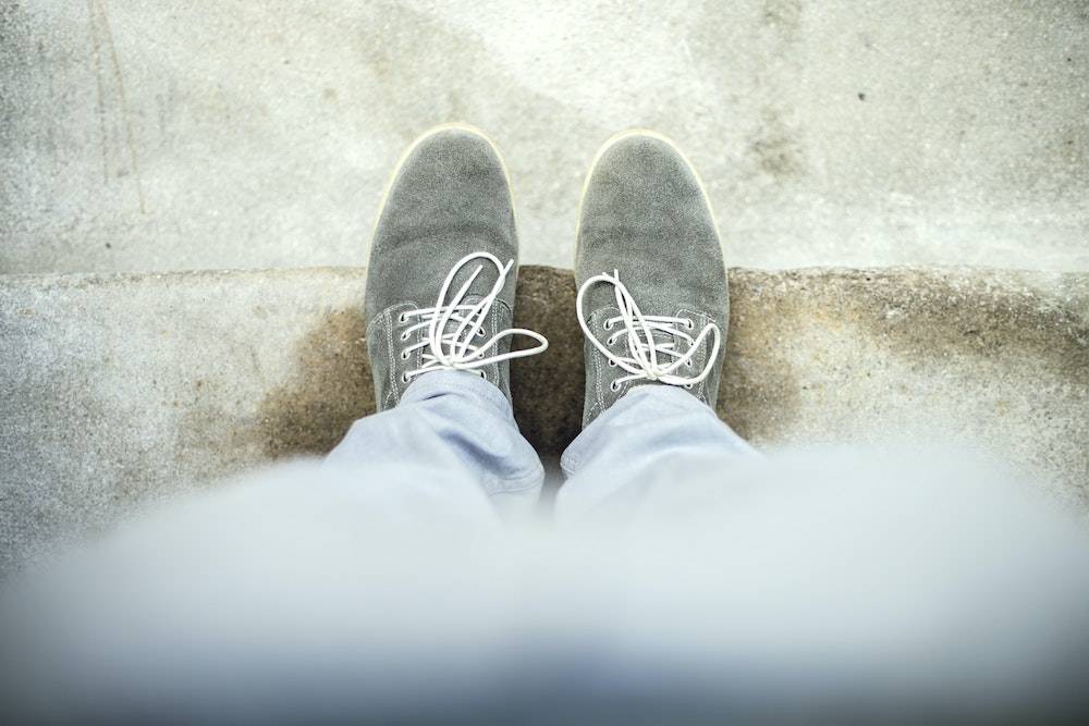 two shoes on a street curb from above