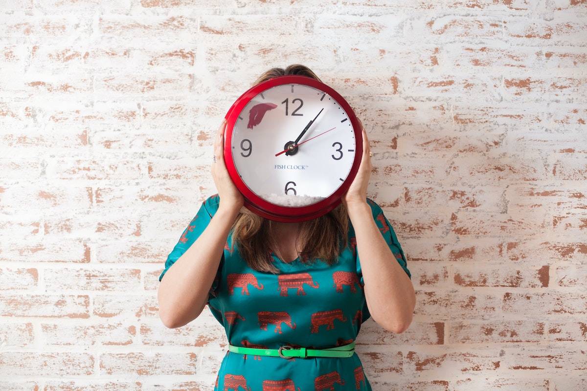 woman holding clock in front of her face