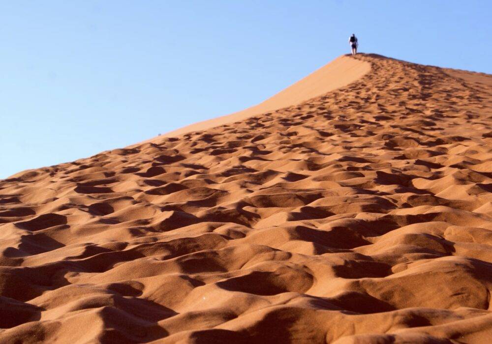 a person at the top of a tall sand dune