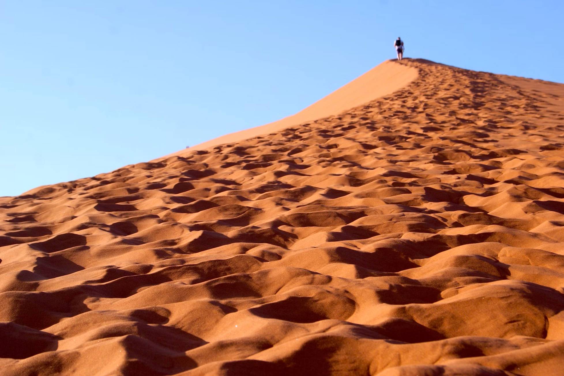 a person at the top of a tall sand dune