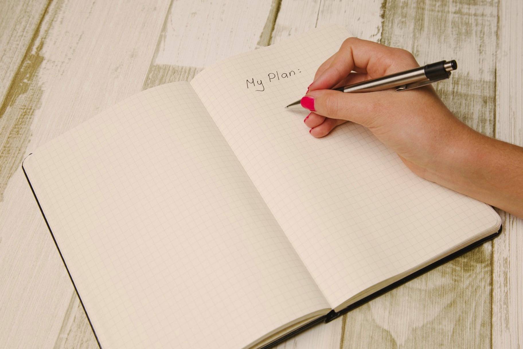 a woman writing in a journal, at the top of the page it says "my plan"
