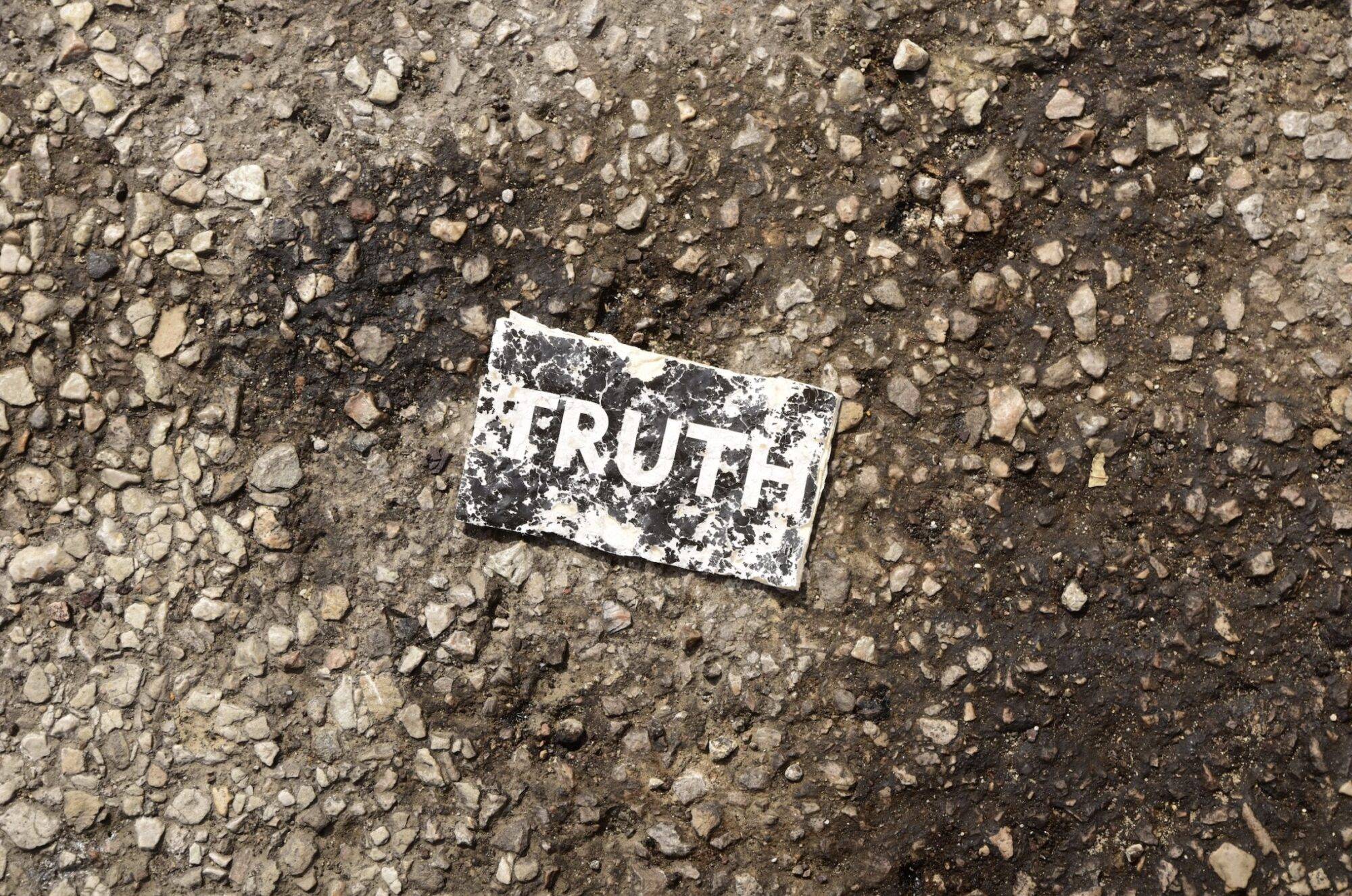 sticker on the asphalt that says "truth"