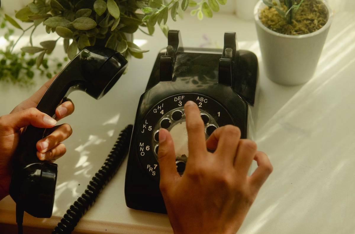 person dialing on an old rotary phone