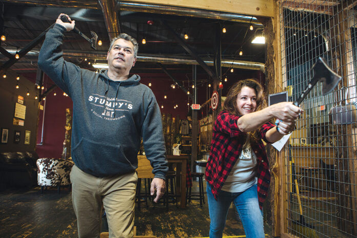 THROWING DOWN: Bryan and Kim Besse, owners of Stumpy’s Hatchet House in Fall River, toss hatchets in one of the business’s eight throwing pits. Kim Besse says the hatchet-throwing entertainment business hosts single participants, parties and corporate events. /PBN PHOTO/RUPERT WHITELEY THROWING DOWN: Bryan and Kim Besse, owners of Stumpy’s Hatchet House in Fall River, toss hatchets in one of the business’s eight throwing pits. Kim Besse says the hatchet-throwing entertainment business hosts single participants, parties and corporate events. /PBN PHOTO/RUPERT WHITELEY