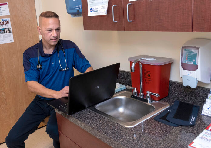 INUNDATED: Dr. Brian Kwetkowski is a general practitioner with his own practice in East Greenwich. Since the onset of COVID-19, he has been inundated with calls from patients and nonpatients seeking authorization for tests, as well as other medical problems. / PBN PHOTO/MICHAEL SALERNO INUNDATED: Dr. Brian Kwetkowski is a general practitioner with his own practice in East Greenwich. Since the onset of COVID-19, he has been inundated with calls from patients and nonpatients seeking authorization for tests, as well as other medical problems. / PBN PHOTO/MICHAEL SALERNO