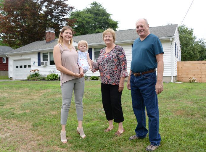 NEW HOME: Nicole Tickner with her daughter Lily, and parents George and Judy Vit. They are in front of the South Kingstown house that Tickner bought for them after they moved to Rhode Island to be closer to their granddaughter. / PBN PHOTO/ELIZABETH GRAHAM NEW HOME: Nicole Tickner with her daughter Lily, and parents George and Judy Vit. They are in front of the South Kingstown house that Tickner bought for them after they moved to Rhode Island to be closer to their granddaughter. / PBN PHOTO/ELIZABETH GRAHAM