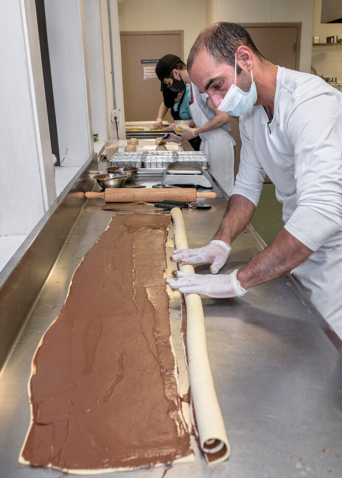 SWEET ROLE: Guy Hanuka, foreground, owner of Buns Bakery, in production mode at the Hope & Main commercial kitchen in Warren, makes babka. In the background are Morgan Moats and John Wilda. / PBN PHOTO/MICHAEL SALERNO