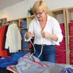 GLOBAL VIEW: Susan Mocarski, founder and owner of Cleverhood LLC, prepares some of the apparel her company manufactures for her store in Providence. With slumping sales in the U.S. because of the pandemic, she’s put more of her focus on boosting sales abroad. / PBN PHOTO/ELIZABETH GRAHAM