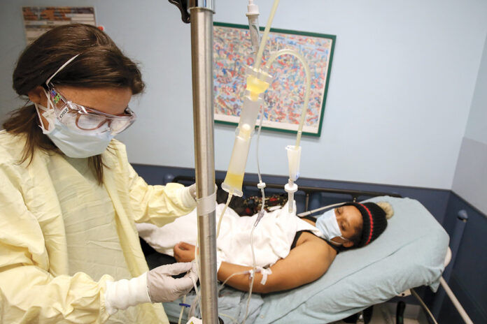CLOSE WATCH: Registered nurse Jessica Pace, left, who works in the Rhode Island Hospital and Hasbro Children’s Hospital Emergency Department, checks the intravenous line of Dolce Contreras, 32, of Central Falls, who is receiving convalescent plasma therapy as part of a clinical trial on its effectiveness against COVID-19. / COURTESY LIFESPAN CORP./WILLIAM MURPHY CLOSE WATCH: Registered nurse Jessica Pace, left, who works in the Rhode Island Hospital and Hasbro Children’s Hospital Emergency Department, checks the intravenous line of Dolce Contreras, 32, of Central Falls, who is receiving convalescent plasma therapy as part of a clinical trial on its effectiveness against COVID-19. / COURTESY LIFESPAN CORP./WILLIAM MURPHY