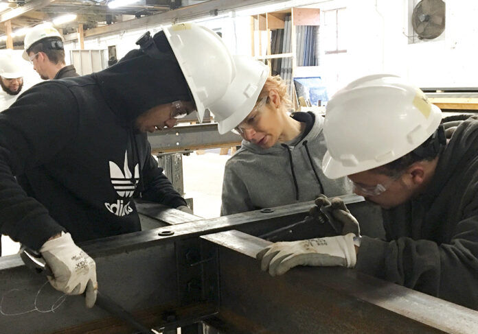 TEAMWORK: Robert Tolson, left, Lisa Silvio and Kyle Brown, right, line up beams to be bolted as part of the ironworking segment of Building Futures’ five-week pre-apprenticeship in 2019. Participants construct a 70-foot-by-14-foot project that contains many of the tools, materials and techniques used in building steel structures. / COURTESY BUILDING FUTURES TEAMWORK: Robert Tolson, left, Lisa Silvio and Kyle Brown, right, line up beams to be bolted as part of the ironworking segment of Building Futures’ five-week pre-apprenticeship in 2019. Participants construct a 70-foot-by-14-foot project that contains many of the tools, materials and techniques used in building steel structures. / COURTESY BUILDING FUTURES